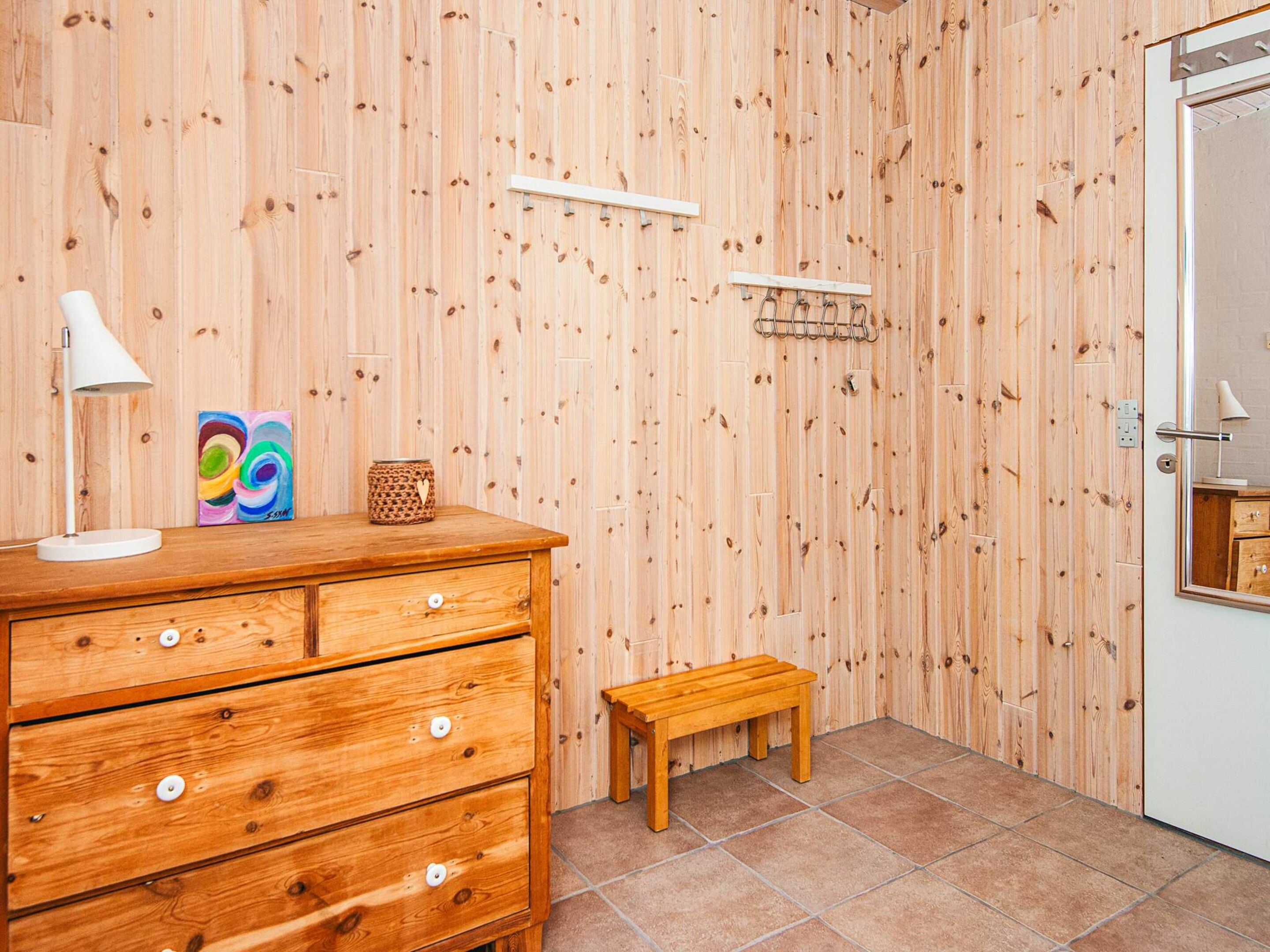 Una habitación de madera con un aparador, un banco y una puerta.