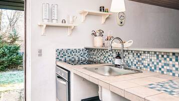 A modern kitchen with a tiled backsplash, a built-in dishwasher, and a hanging light fixture.