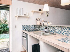 Una cocina moderna con salpicadero de azulejos, lavavajillas integrado y una lámpara colgante.