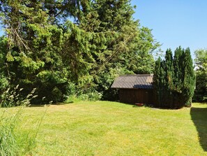 A rustic wooden cabin with a metal roof, surrounded by lush greenery and tall trees. - 2 Person Holiday Home in Tarm (Tarm)