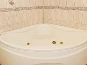 A bathtub with two control knobs, surrounded by beige tiles with a floral border. - 8 Person Holiday Home in Oksbol-by Traum (Oksbol)