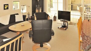A modern living room with a sofa, a black leather chair, a wooden coffee table, and a TV on a stand.
