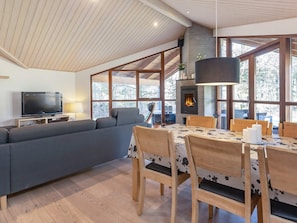 Uma sala de estar moderna com sofá, televisão, mesa de jantar, cadeiras e lareira.