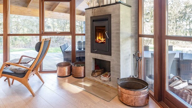 A modern interior with a fireplace, wooden flooring, and large windows offering a view of the outdoors. - 4 Star Holiday Home in Skals (Skals)