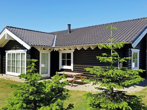 A log cabin with a dark exterior, white trim, a chimney, and a small porch with a bench. - 4 Star Holiday Home in Sydals (Sydals)