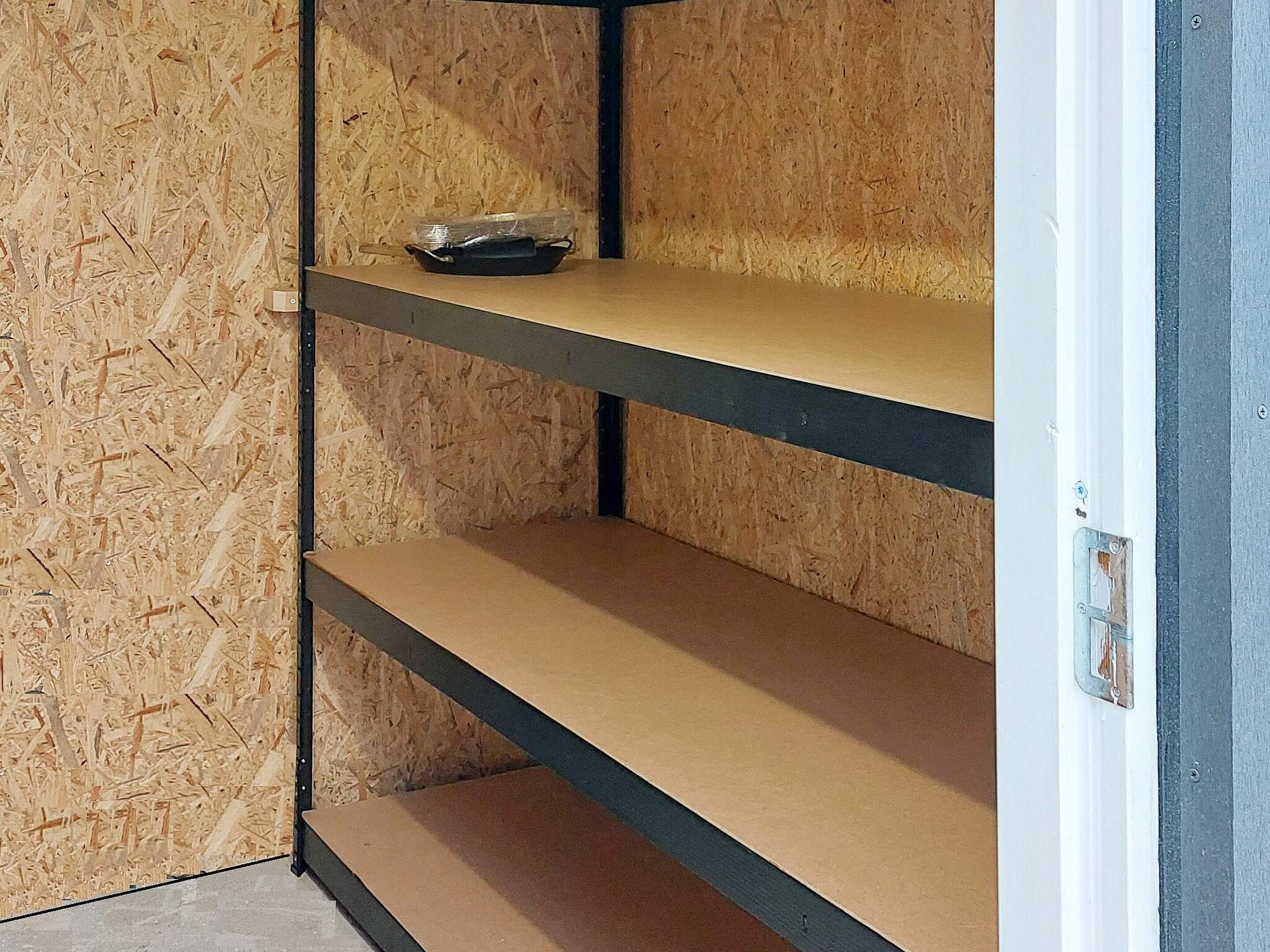 Un coin de pièce avec un mur en bois et une étagère en métal.
