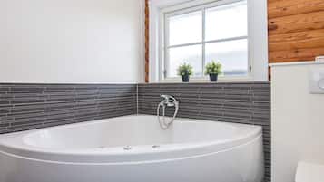 Et badeværelse med et fristående badekar, toilet og et vindue med plantekasser.