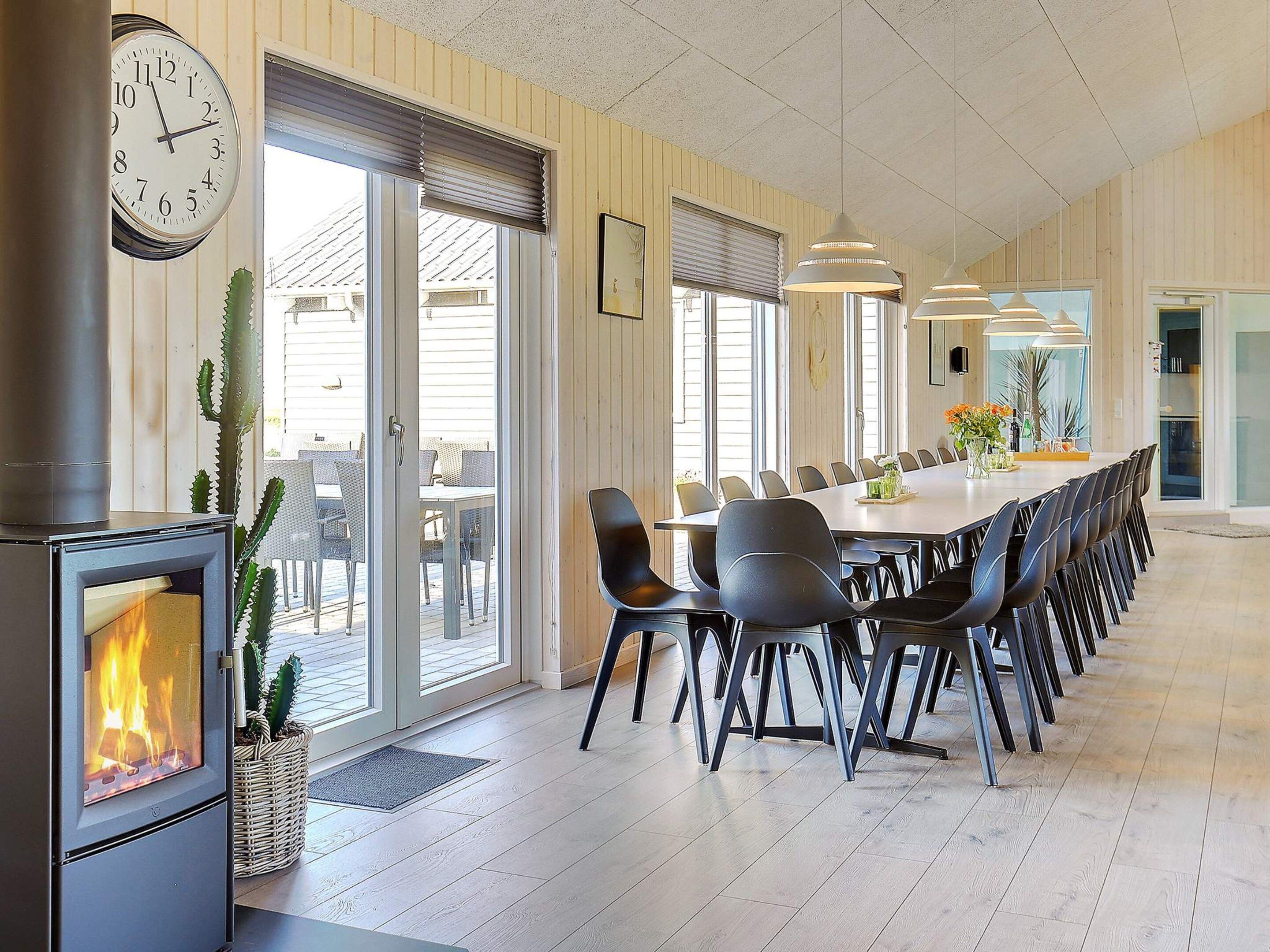 Un comedor espacioso con una mesa larga y sillas, una chimenea y ventanas amplias.