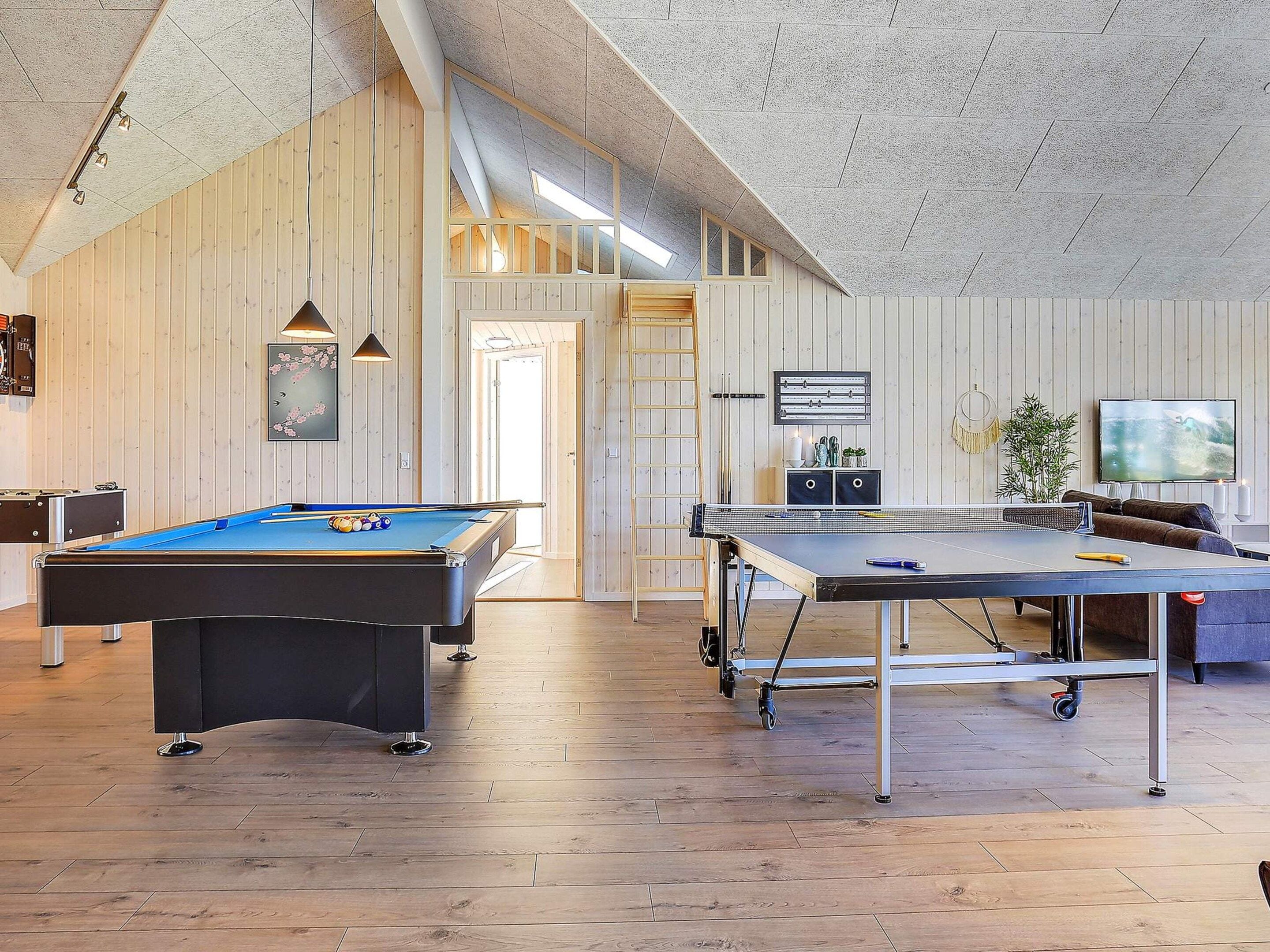 A recreational room with a pool table, ping pong table, and a billiards table.