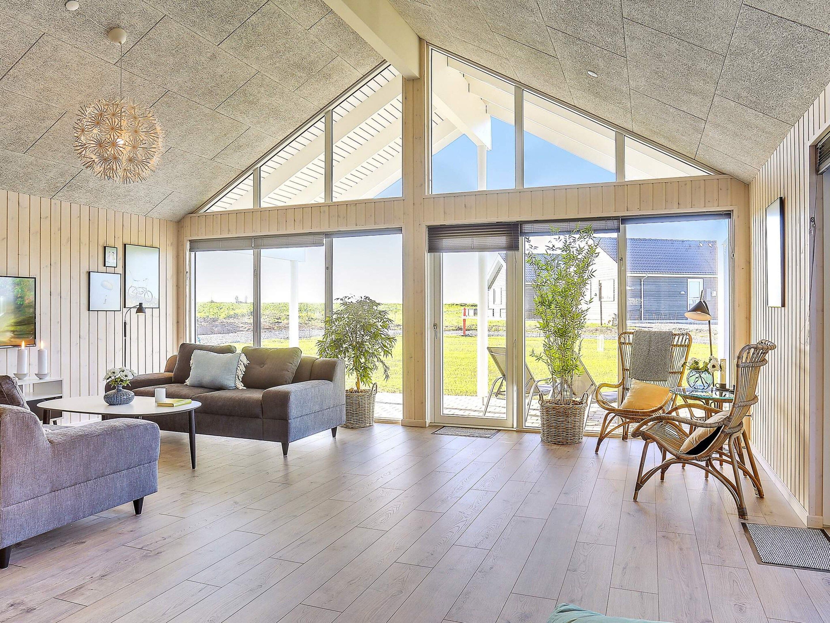 A spacious living area with a large window, a sofa, a coffee table, and a wicker chair.