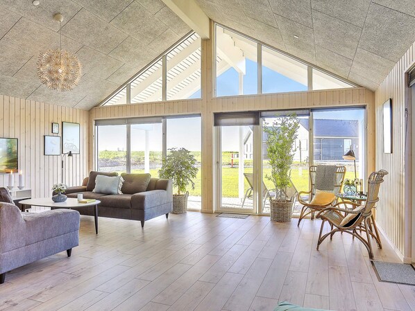 A spacious living area with a large window, a sofa, a coffee table, and a wicker chair.
