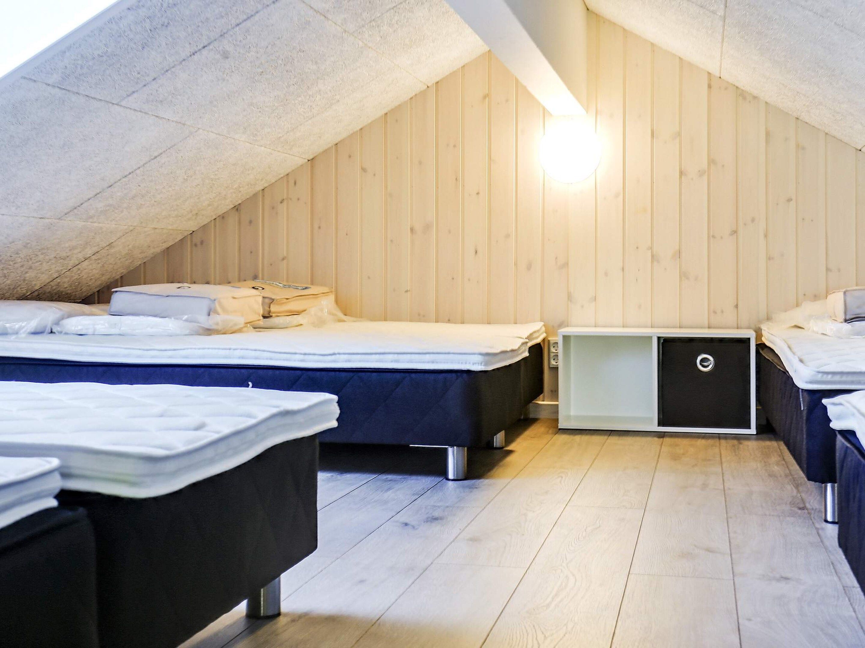 A room with two beds, a small cabinet, and a sloped ceiling.