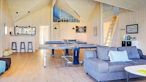 A spacious living area with a ping pong table, a sofa, and a staircase. - 5 Star Holiday Home in Bogense (Bogense)