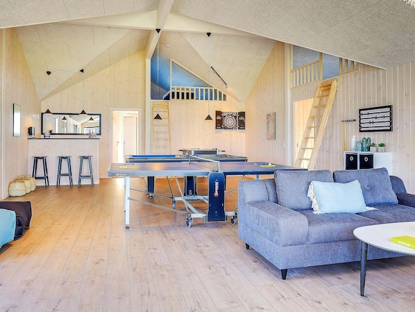 A spacious living area with a ping pong table, a sofa, and a staircase. - 5 Star Holiday Home in Bogense (Bogense)
