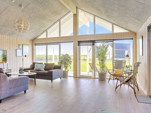A spacious living area with a high ceiling, large windows, and a view of the outdoors. - 5 Star Holiday Home in Bogense (Bogense)