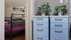 A bedroom with a bed, a dresser with drawers, a shelf with items, and two potted plants. - 6 Person Holiday Home in Vara (Vara)
