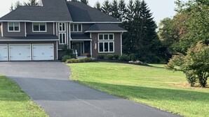 A two-story house with a driveway leading to a garage. - Deer Run Lodging House (Skaneateles)