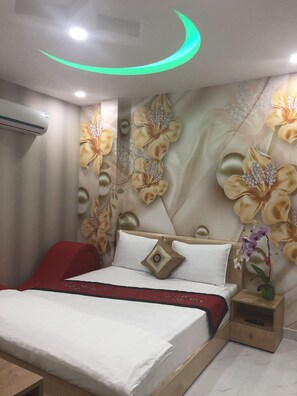 A bedroom with a bed, a nightstand, and a wall with floral wallpaper.