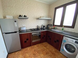 A compact kitchen with a refrigerator, stove, oven, and washing machine.