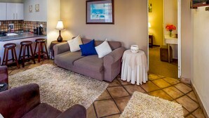 Ein Wohnzimmer mit einer Couch, einem Couchtisch und einer Küchenzeile im Hintergrund.