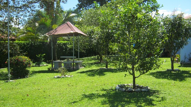 A gazebo with a tiled roof, surrounded by a well-maintained lawn and various trees. - Apartamento Completo a 2 Minutos Ruta 32 (Jimenez)