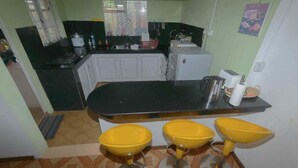 Una cocina compacta con encimera negra, armarios blancos y un lavamanos amarillo.