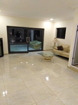 Relax in this open-plan living space with a sofa and glass coffee table, perfect for unwinding.