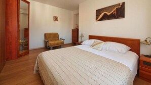 Une chambre à coucher avec un grand lit, une chaise, une commode et un miroir.