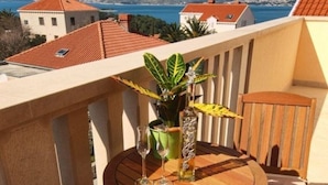 Un balcon avec une table et des chaises en bois, une plante en pot et une bouteille.