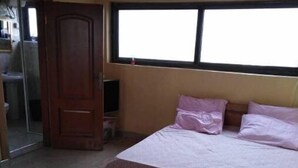 Ein Schlafzimmer mit Bett, Fenster und Tür zu einem Badezimmer.