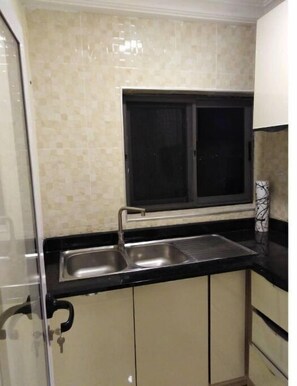 Kitchen area with double sink and light-colored cabinets.
