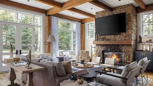 A spacious living room with a stone fireplace, comfortable seating, and large windows offering a view of the outdoors. - Outpost: Granite Ridge Lodge 1: Private Hot Tub (Jackson)