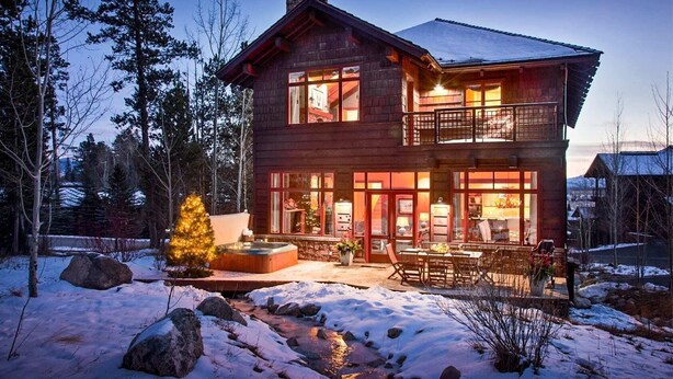 A two-story log cabin with a balcony, surrounded by snow and trees. - Outpost: Granite Ridge Lodge 1: Private Hot Tub (Jackson)