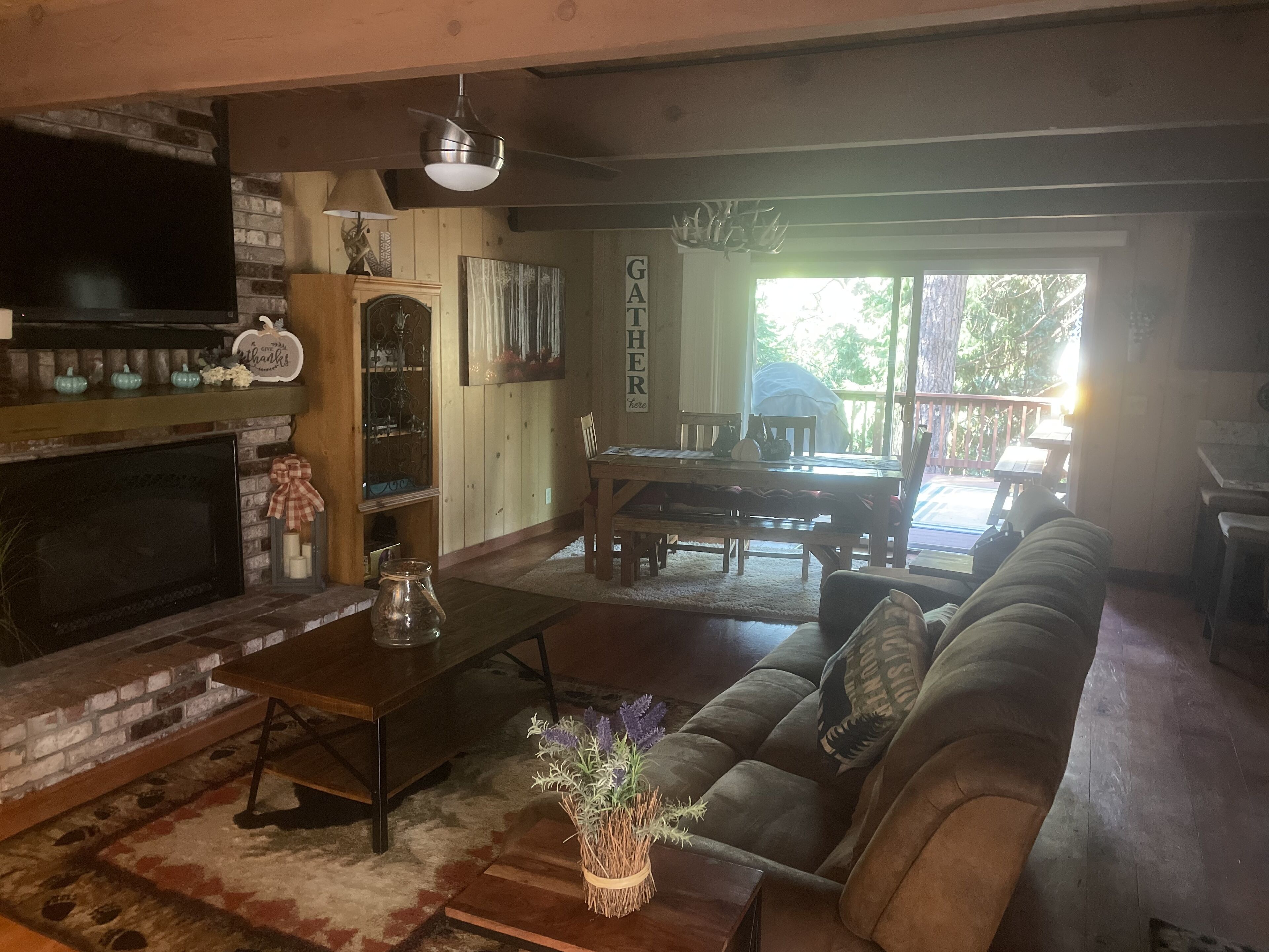 A cozy living room with a fireplace, a dining area, and a large window.