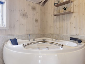 A modern bathroom with a freestanding bathtub, wooden wall paneling, and a small shelf with decorative items. - 6 Person Holiday Home in Hadsund-by Traum (Hadsund)
