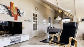 A modern living room with a flat-screen TV, a dining table with chairs, and a kitchen area in the background. - 6 Person Holiday Home in Hadsund-by Traum (Hadsund)