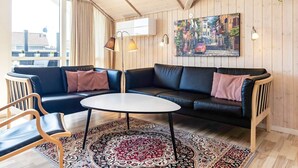 A cozy living room with a black leather sofa, a round coffee table, and a patterned rug. - 6 Person Holiday Home in Hadsund-by Traum (Hadsund)
