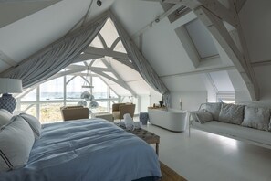 Une chambre moderne avec un grand lit, un canapé, une salle de bain et une vue sur la plage.