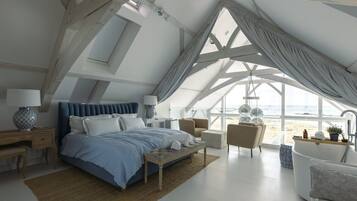 Un dormitorio con una cama grande, un escritorio, una silla y vistas a la playa.