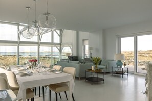A modern dining area with a table set for a meal, a sofa, and a view of the outdoors.