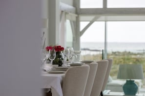 Une table à manger dressée pour quatre personnes, avec vue sur la mer.