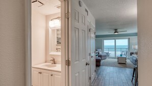 A hallway leading to a bathroom with a sink and mirror, a living area with a sofa and a view of the outdoors. - Tier 1. Oceanfront 2 bedroom, 2.5 bath townhouse. (St. Augustine)