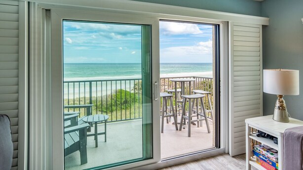 A room with a large sliding glass door leading to a balcony with a view of the ocean and beach. - Tier 1. Oceanfront 2 bedroom, 2.5 bath townhouse. (St. Augustine)