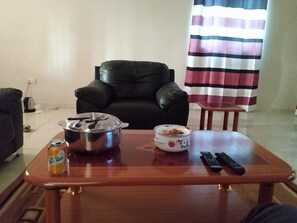 Relax in this cozy living space with a comfortable armchair, coffee table, and television.