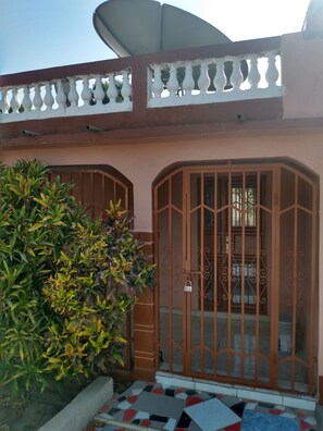 Secure entrance with ornate metal gate, elegant balcony, and lush garden.