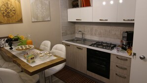 A modern kitchen with white cabinetry, a wooden countertop, and a dining area with white chairs.