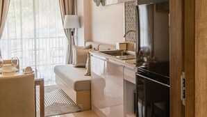 A modern kitchen with a black refrigerator, a dining area with a table and chairs, and a sofa. - Palmetto Condominium (Karon)