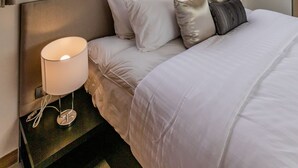 A hotel room with a bed, white bedding, a bedside lamp, and sheer curtains. - Palmetto Condominium (Karon)