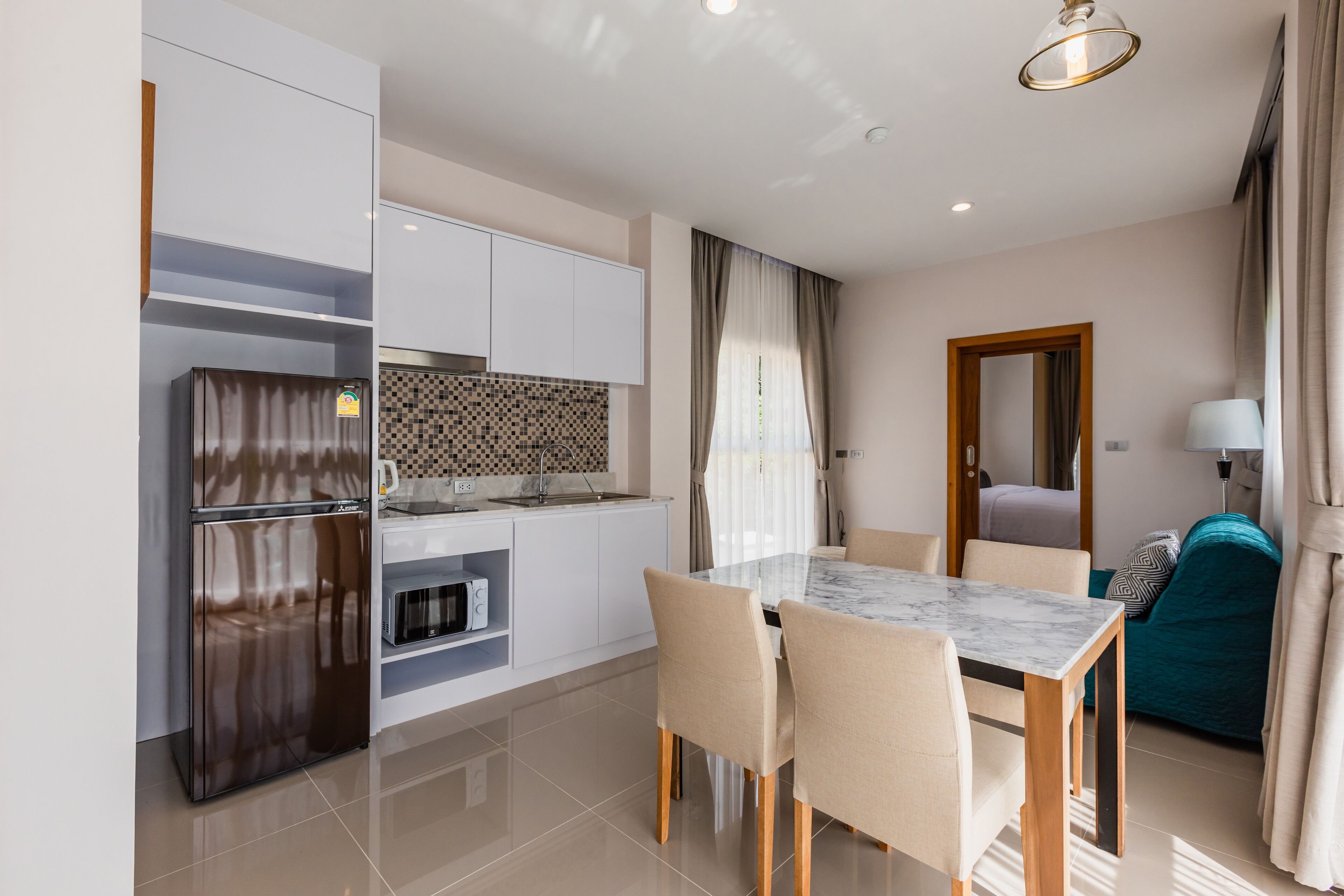 Una cocina moderna con armarios blancos, horno integrado y una mesa de comedor de mármol con cuatro sillas.