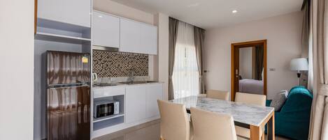 Una cocina moderna con armarios blancos, horno integrado y una mesa de comedor de mármol con cuatro sillas.